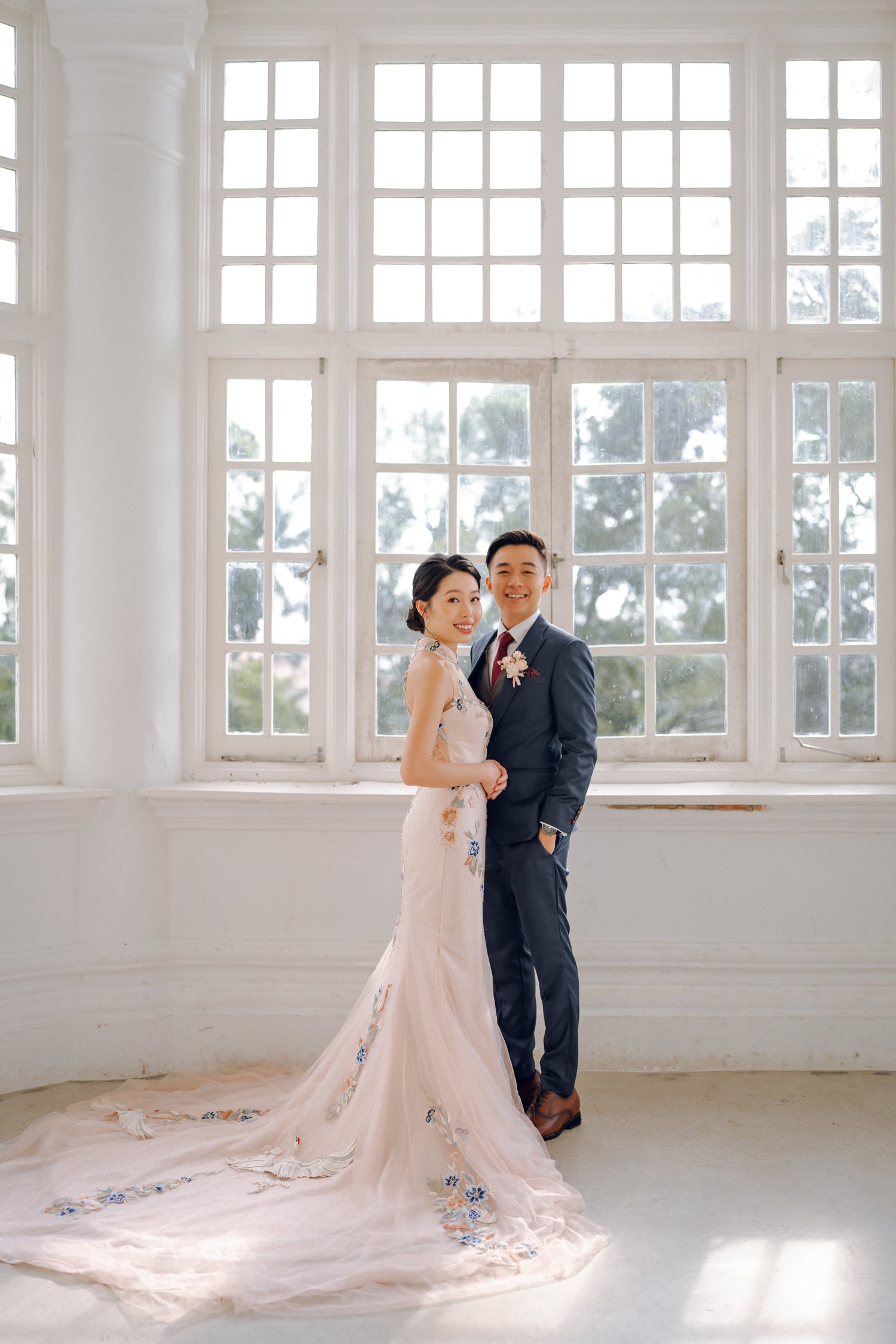 WeddingCrafters bride wearing a modern floral wedding cheongsam beside her groom