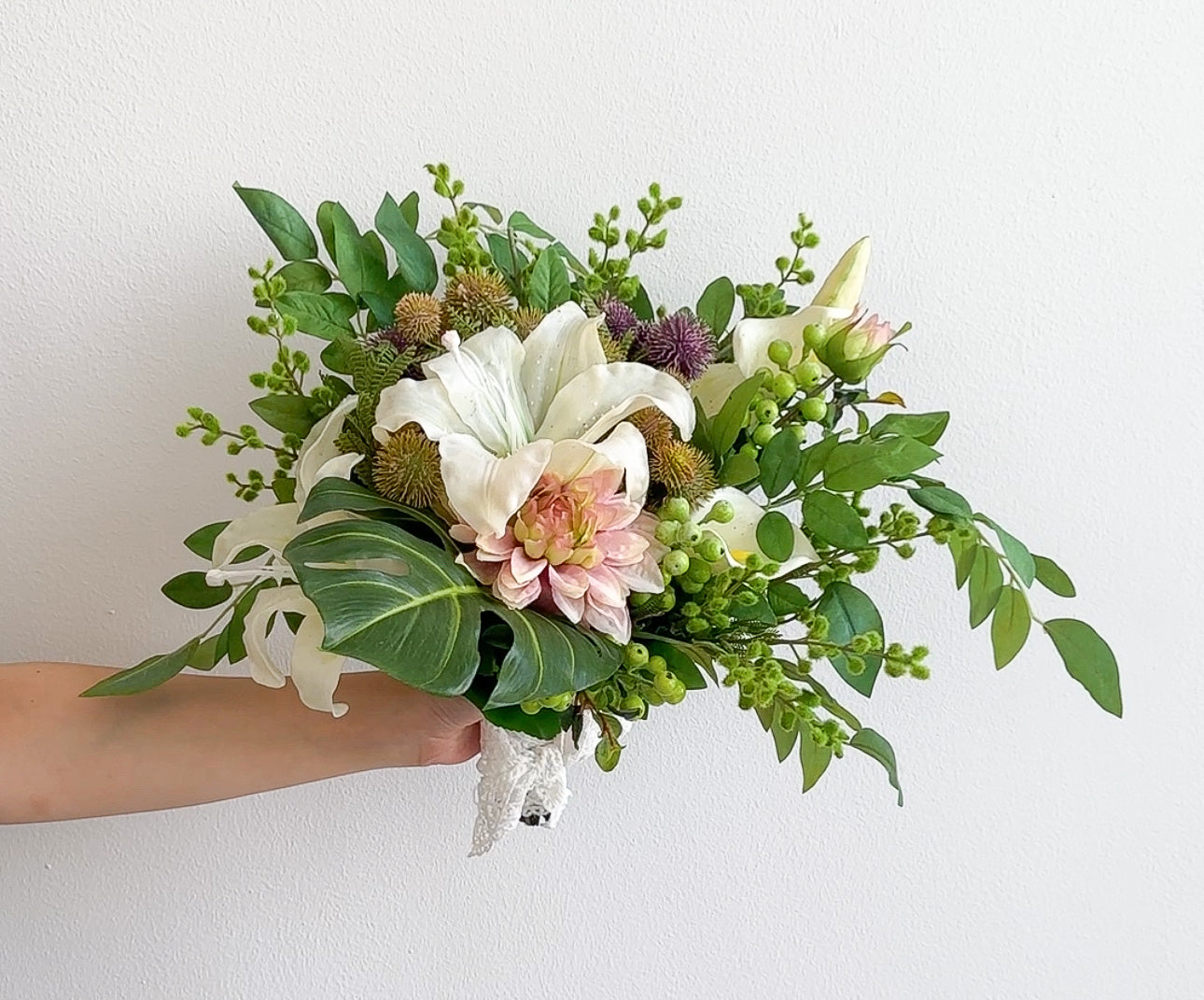 Hand holding a bouquet of flowers against a white background
