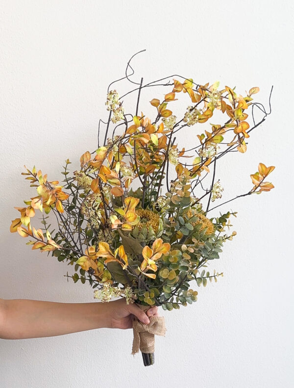 Bouquet of yellow and green flowers held by a person against a white background