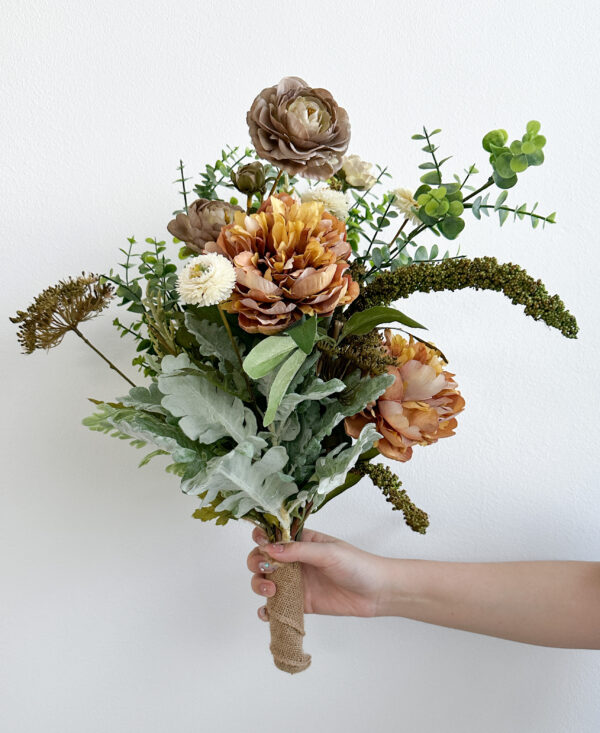 Hand holding a bouquet of flowers against a white background
