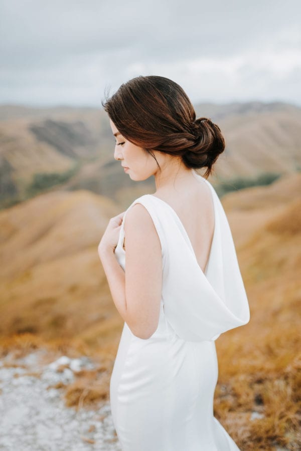 Back view of a custom-made minimalist wedding gown by WeddingCrafters featuring an elegant draped open-back design.