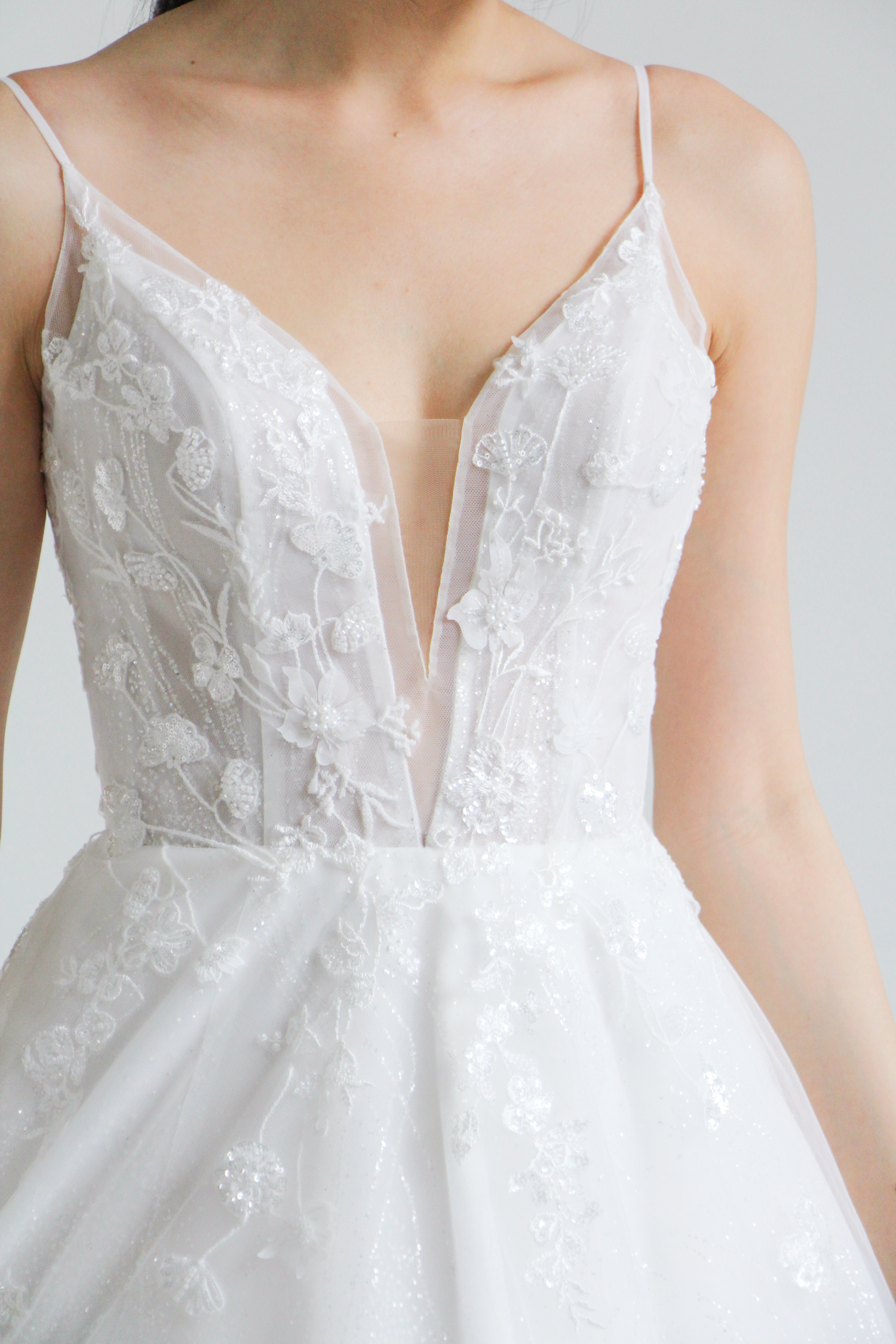 Close-up of Caitlyn wedding dress with delicate floral lace and glitter tulle