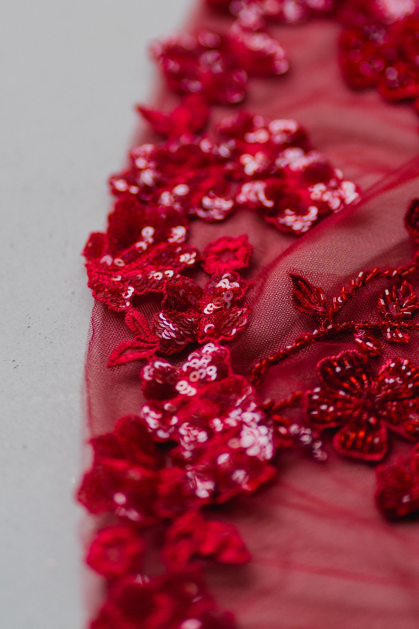 Close-up of Cora bridal cheongsam with intricate red lace appliqué and illusion lace