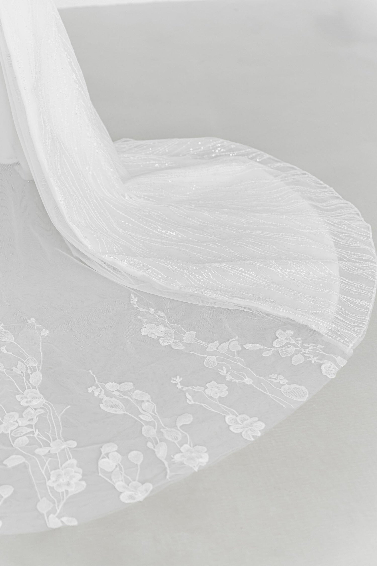 Close-up of Dinna wedding gown highlighting the floral lace peekaboo train
