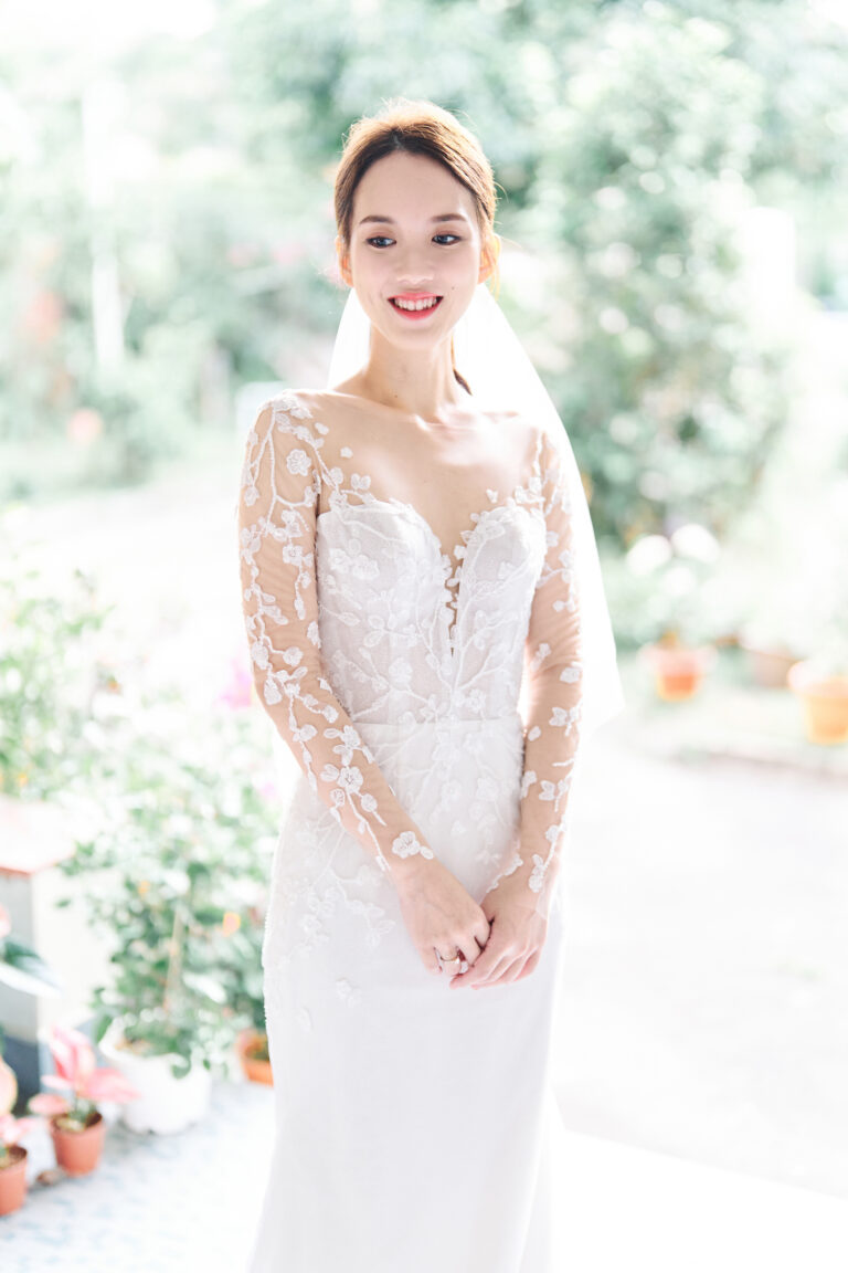 Bride wearing a bespoke lace wedding dress by WeddingCrafters with illusion sleeves and floral lace detailing.