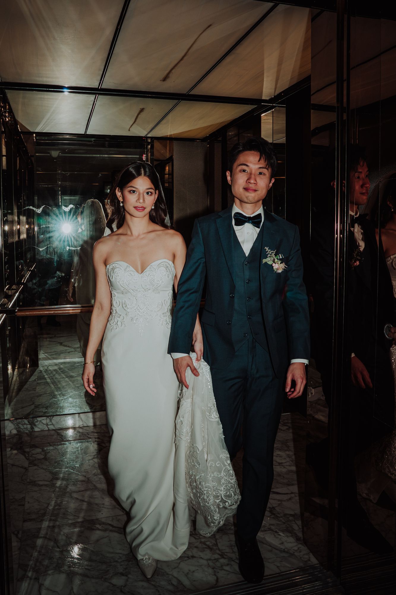 Bride and groom walking together with the bride wearing a sweetheart WeddingCrafters bridal gown